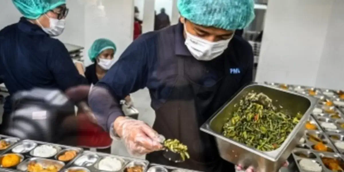Petugas sedang menyiapkan menu makanan pada program Makan Bergizi Gratis (MBG).